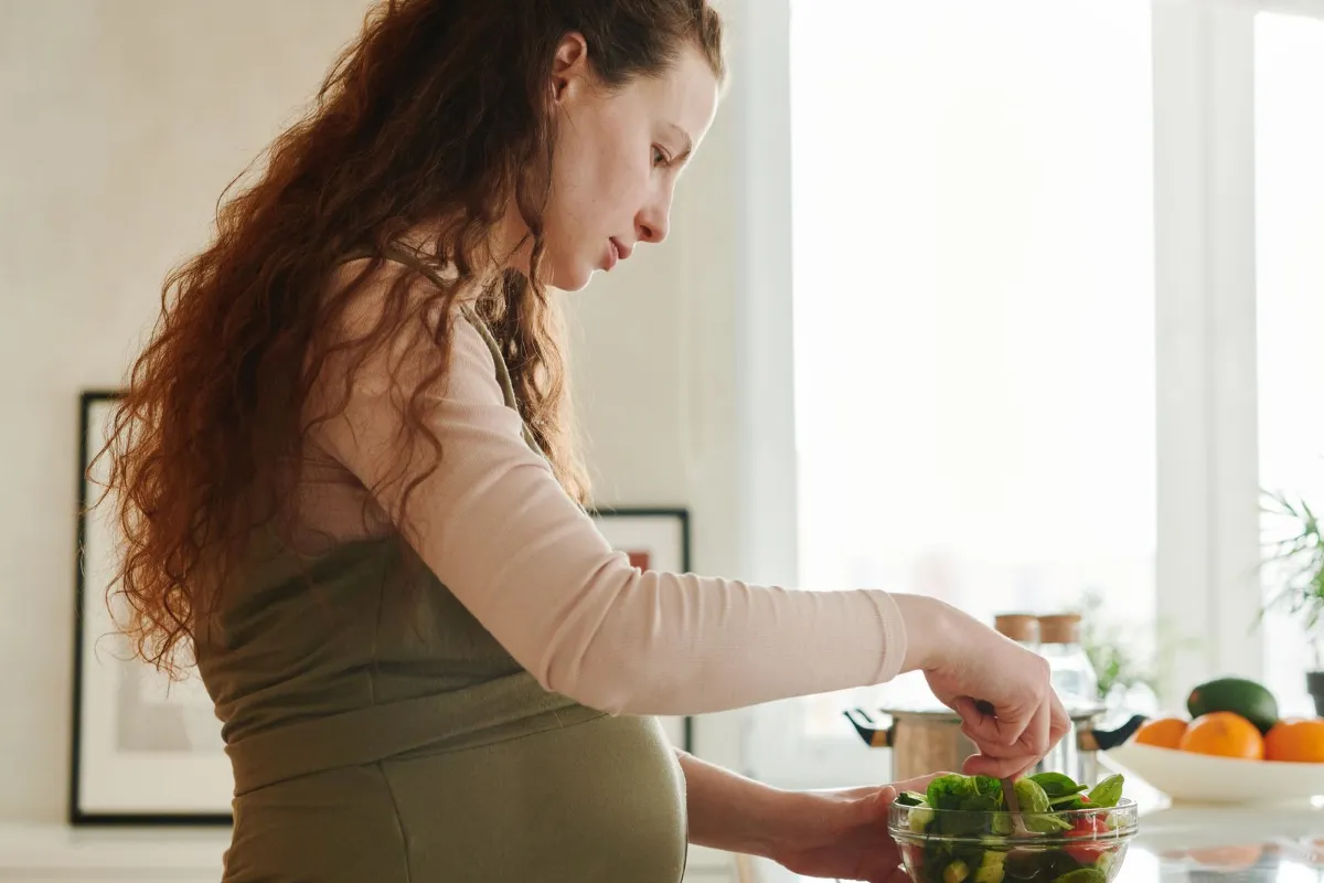 Gestante prepara uma salada na cozinha